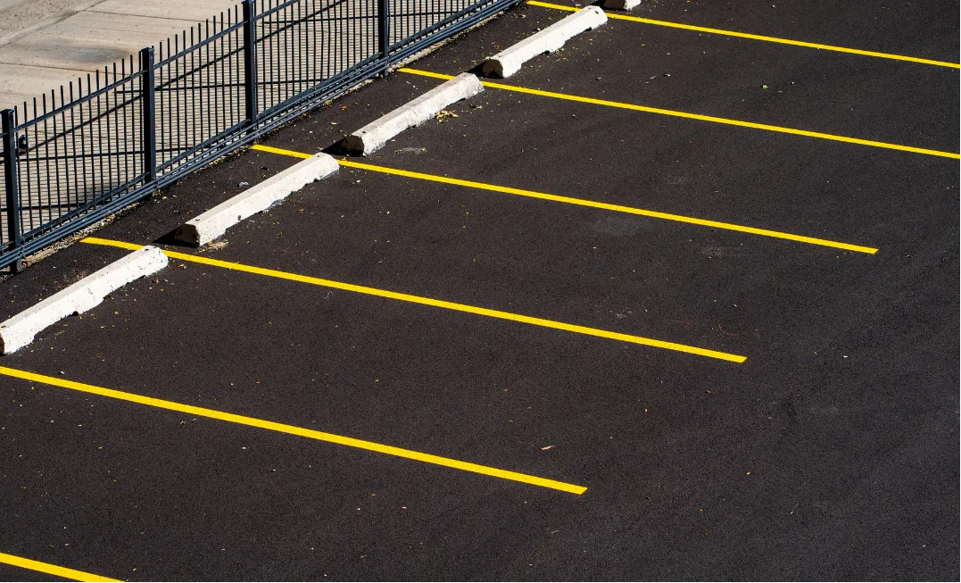 line-striping-1 Empty parking spaces with yellow lines and a metal fence at the side.